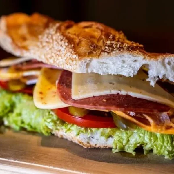 A toasted sesame sub filled with salami, cheese, tomato, pickled peppers and lettuce